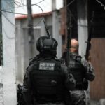 Militariy police officers patrol during the Operacao Contencao (Operation Containment) at the Vila Cruzeiro favela, in the Penha complex, in Rio de Janeiro, Brazil, on October 28, 2025. At least 2,500 security forces agents took part in an operation to arrest drug traffickers from the Comando Vermelho (CV), which resulted in 18 suspects and several police officers dead. (Photo by Mauro PIMENTEL / AFP)